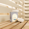Shower steamers packaging on a wooden surface with a blurred background