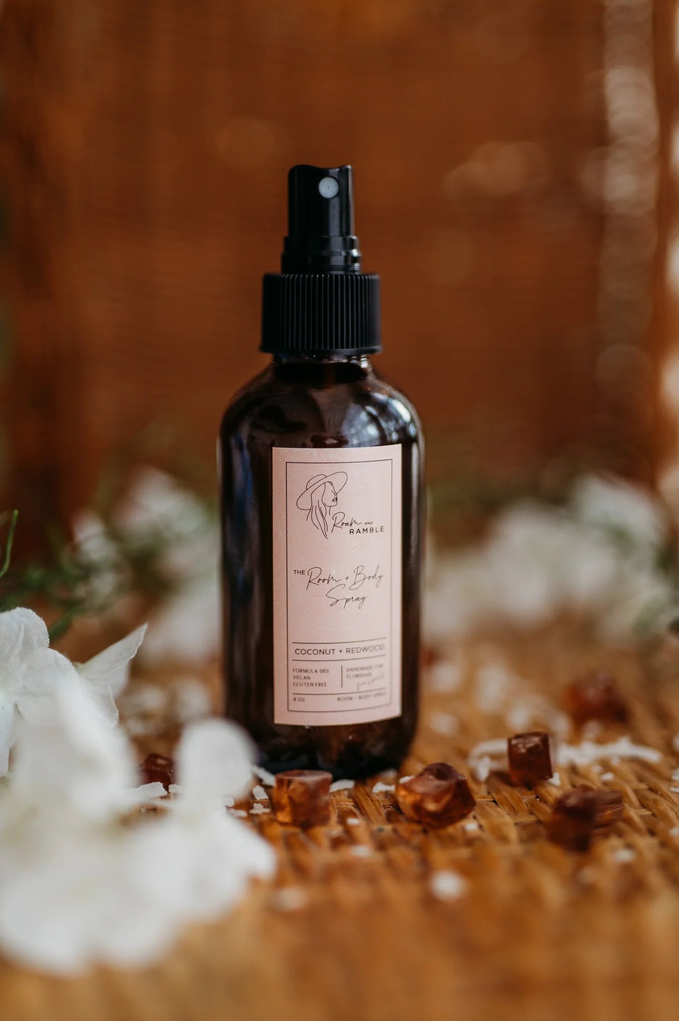 Brown spray bottle with label on a wooden surface with flowers and small brown objects.