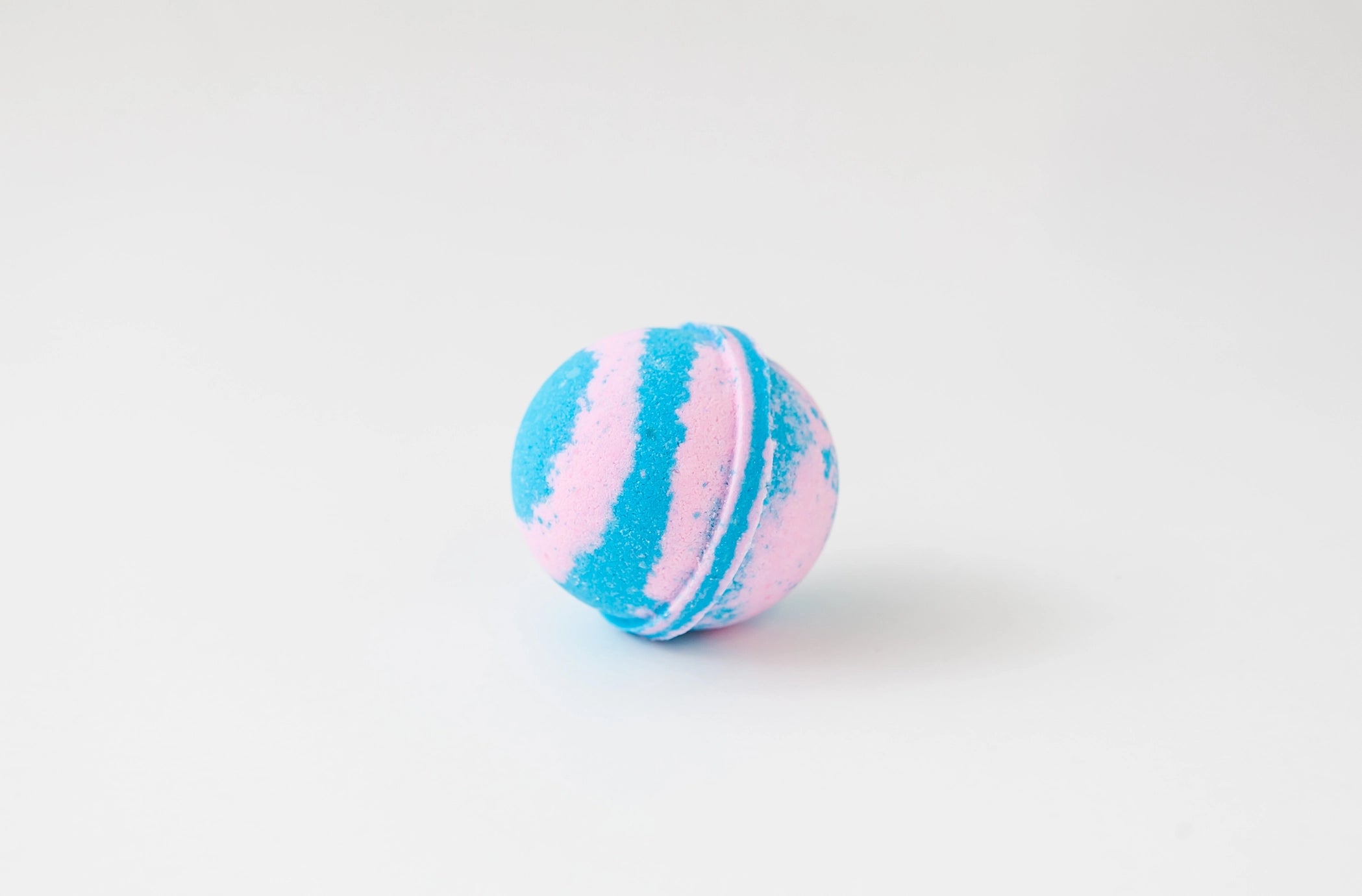 Blue and pink striped bath bomb on a white background
