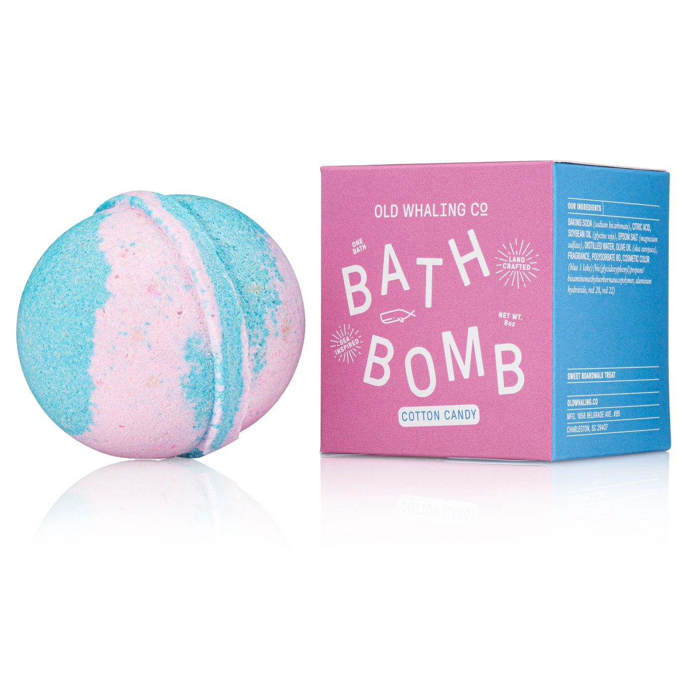Bath bomb with pink and blue colors next to its packaging on a white background