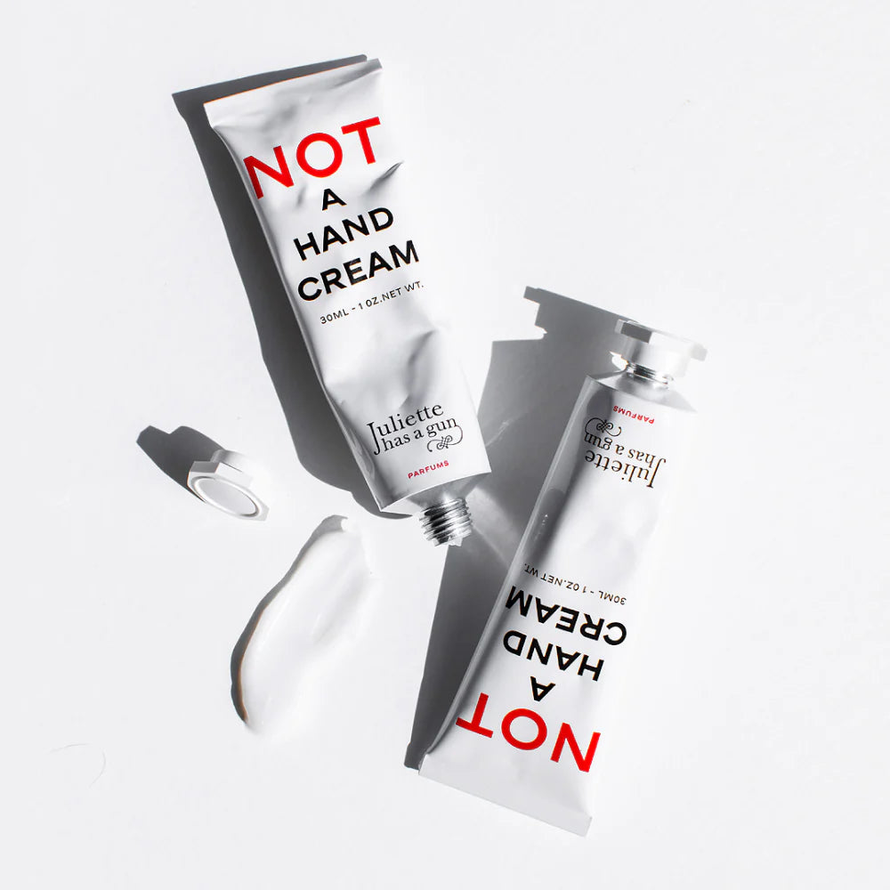 Juliette Has a Gun Not A Hand Cream 30mL, available at Rafa Natural. Products laying down with a lotion smear.