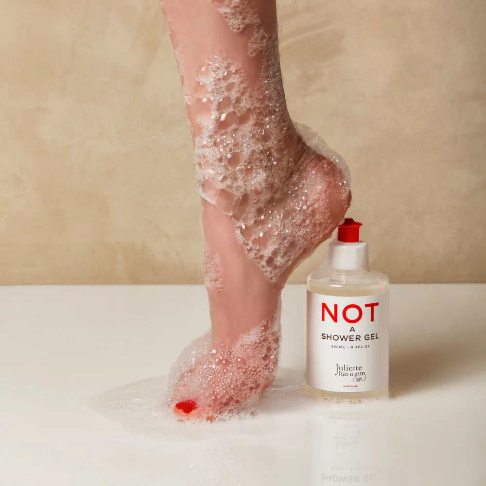 Juliette Has a Gun Not A Shower Gel 250mL, available at Rafa Natural. Foot with red nail polish, and soap suds shown next to the product.