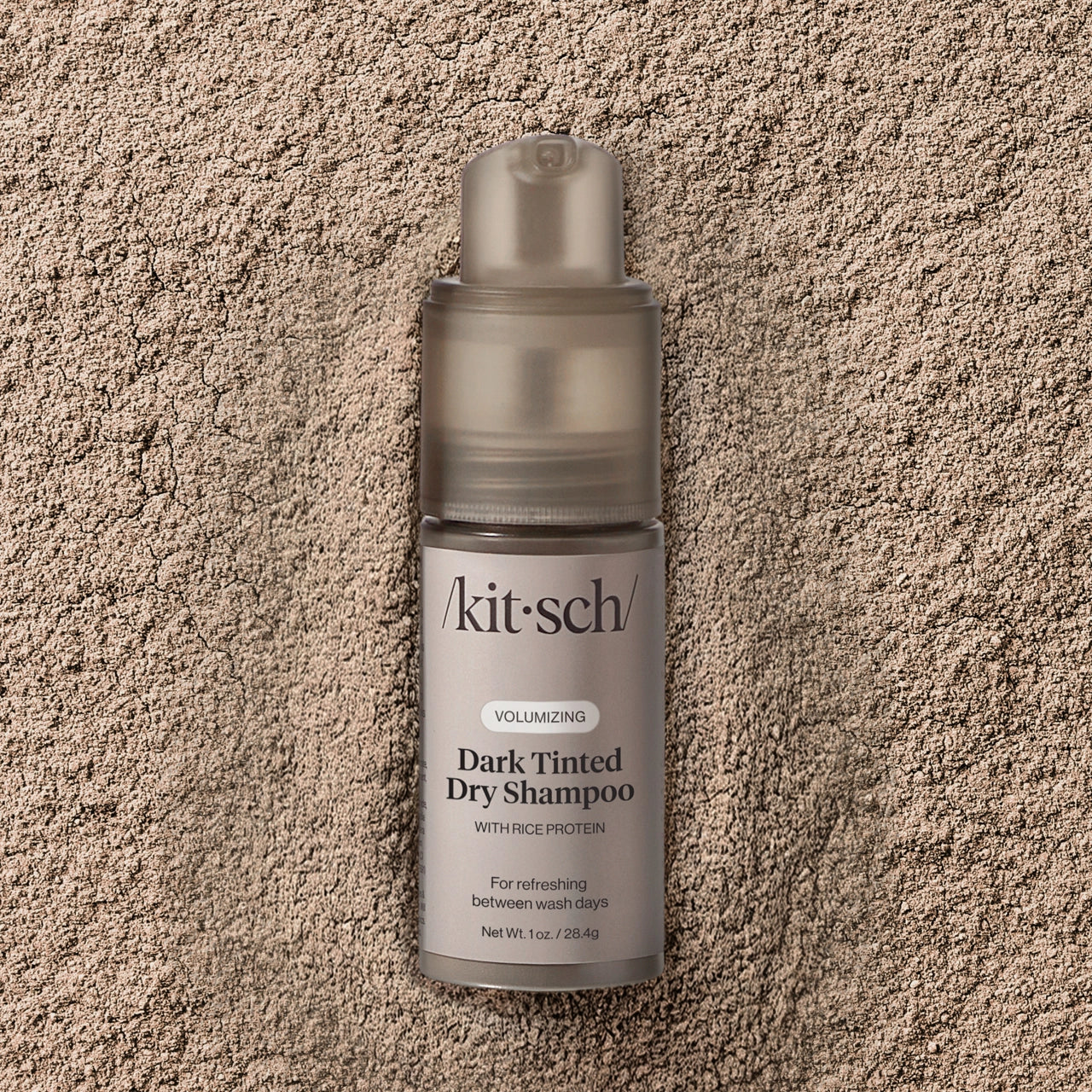 Kitsch dark tinted dry shampoo bottle on a textured beige surface