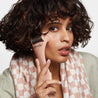 Woman applying ice roller, wearing a checkered scarf
