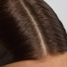 Close-up of a person's head with dark hair and visible part line.