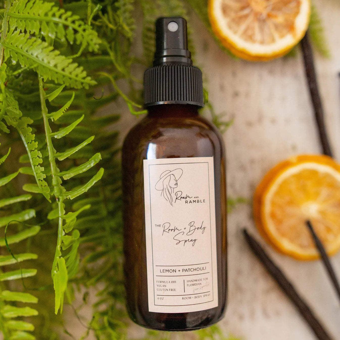 Brown spray bottle with label on a wooden surface with oranges and ferns