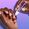 Lavender Nighttime Cuticle Quench being applied to nails against purple background, showing product application