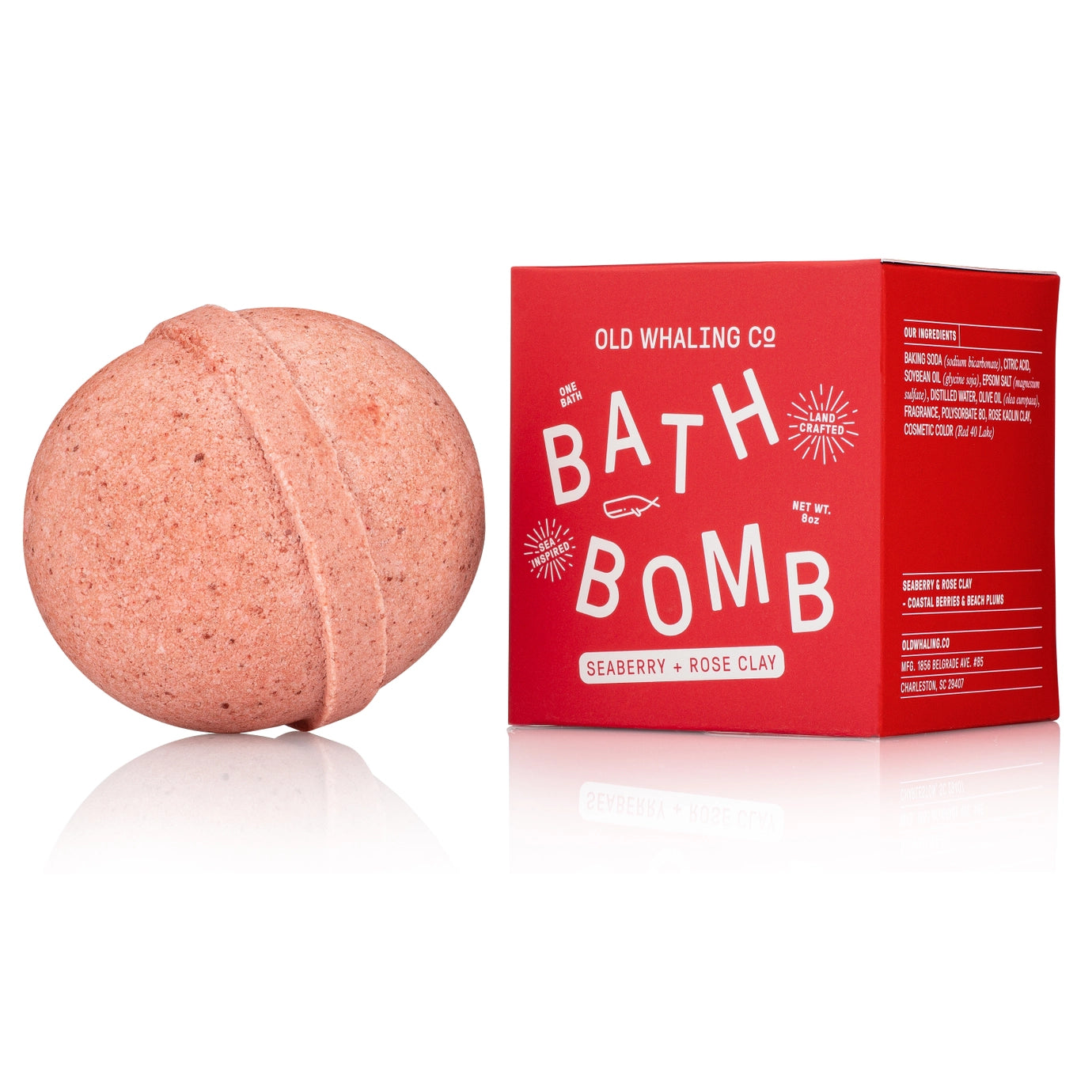 Pink bath bomb next to its red packaging on a white background