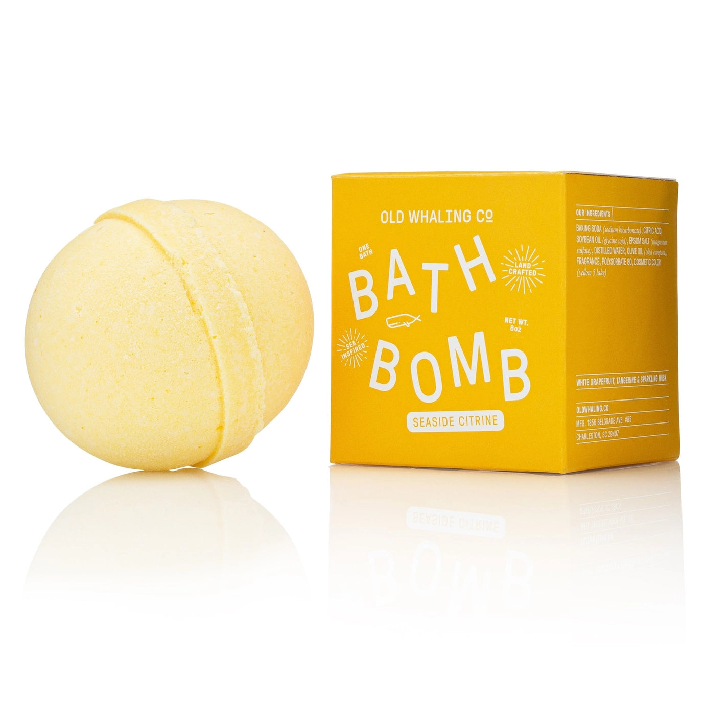 Yellow bath bomb next to its packaging on a white background