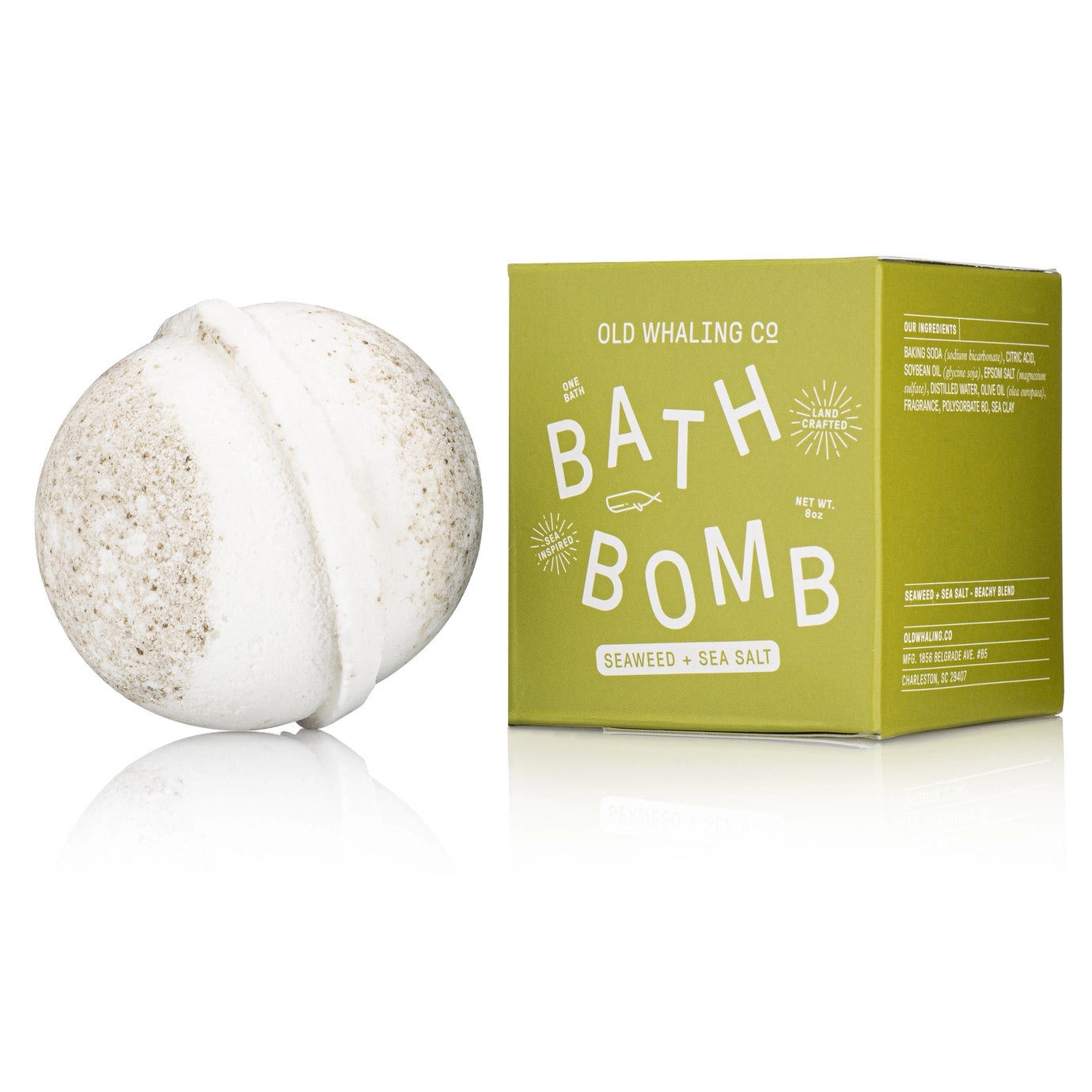 White bath bomb next to its green box packaging on a white background