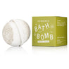 White bath bomb next to its green box packaging on a white background