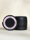 Black container with pink label on a beige background
