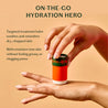 Hand holding a small container with text about targeted treatment balm on a beige background