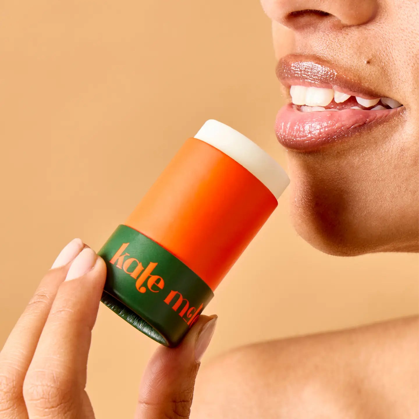 Person holding a balm against a beige background