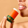 Person holding a balm against a beige background