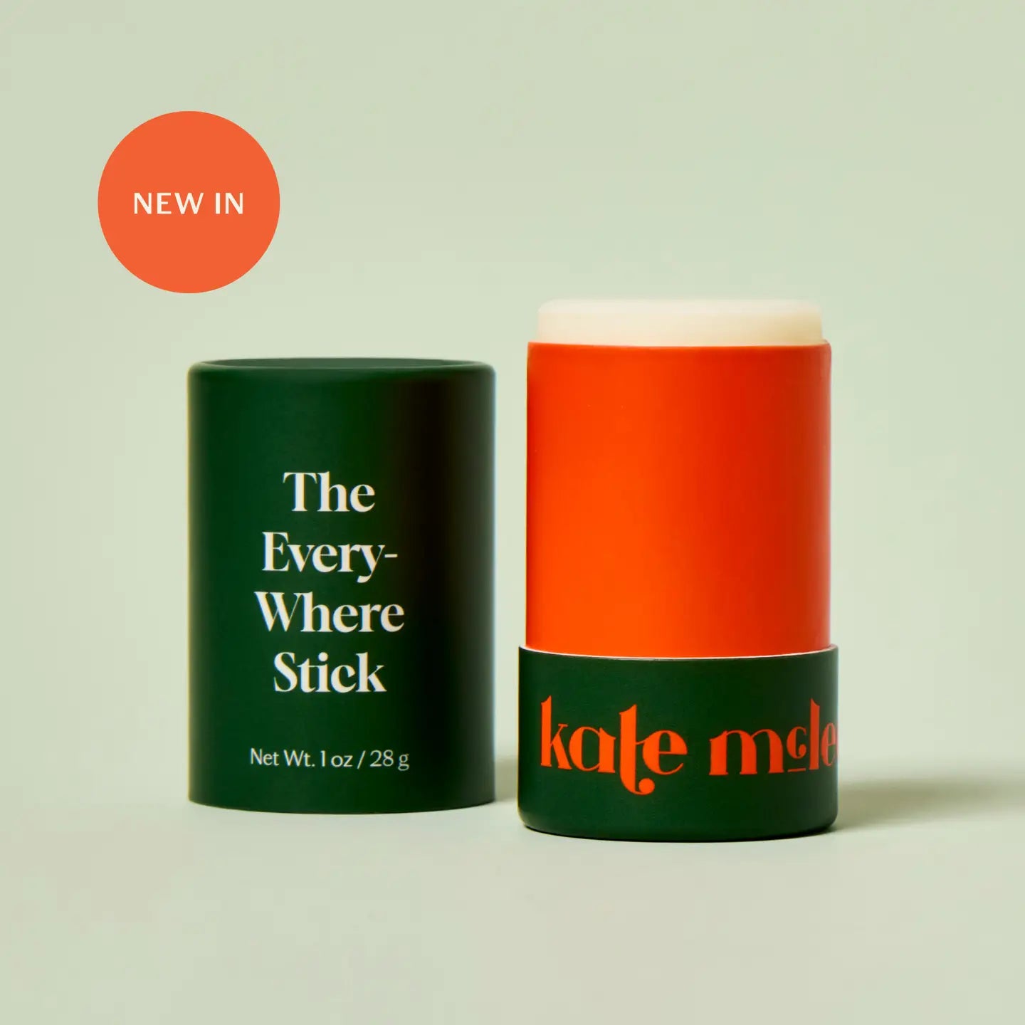 Orange 'Every-Where Stick' by Kate McLeod with green packaging on a light beige background
