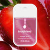 Touchland Berry Bliss Power Mist, in front of a large, halved strawberry.