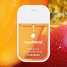 Touchland Mango Passion Power Mist, in front of mango fruits.