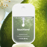 Touchland Rainwater Power Mist in front of fruit and a white flower.