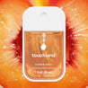 Touchland Velvet Peach Power Mist in front of a halved peach.